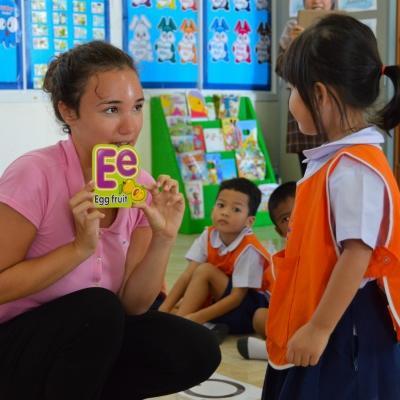 Projects Abroad volunteer teaching English in Thailand helps a young girl with her alphabet Volunteer gains teaching work experience in Thailand while working with children